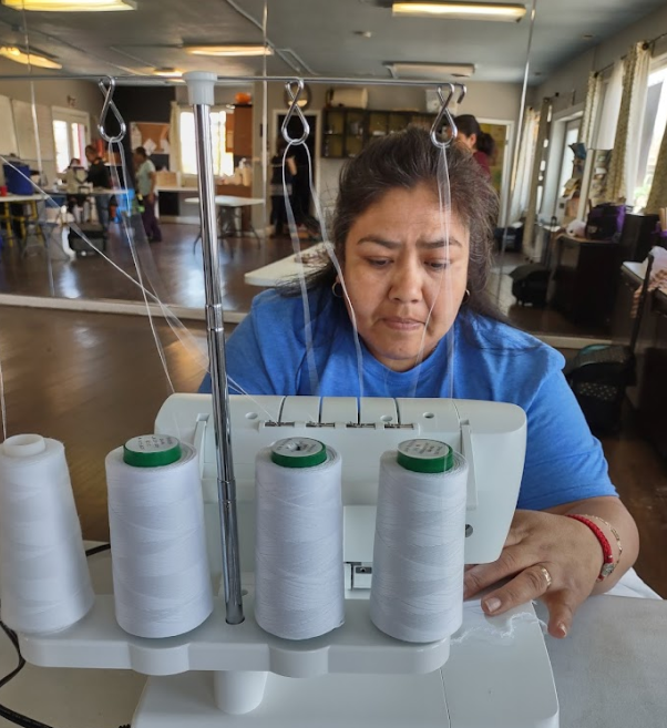 Woman sewing with serger machine in community workshop