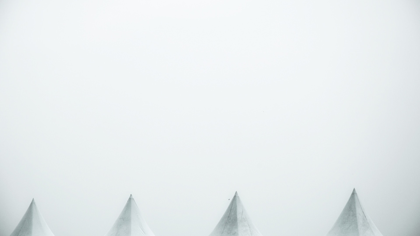 Minimalist photo of three tent peaks emerging from fog