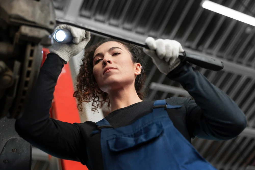 Mecánica inspeccionando un disco de freno con una linterna en el taller {{brizy_dc_image_alt imageSrc=