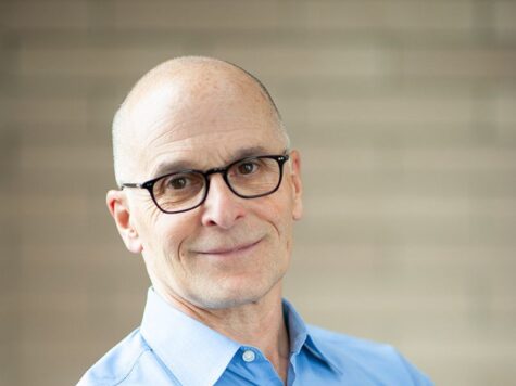 George DeMartino professional headshot, smiling with arms crossed in blue shirt