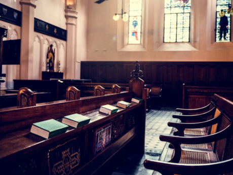 Empty wooden pews inside historic courtroom or church with stained glass windows