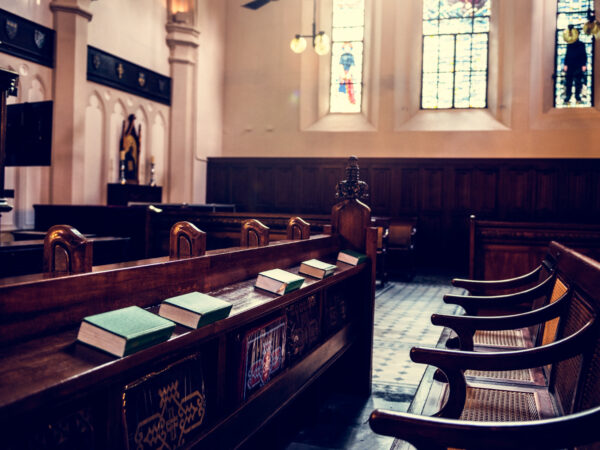 Empty wooden pews inside historic courtroom or church with stained glass windows