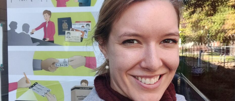 Marion Pellegrin smiling selfie outside polling station poster