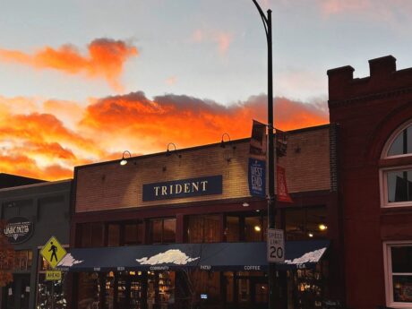 Trident Booksellers & Café storefront at sunset with orange clouds