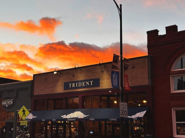 Trident Booksellers & Café storefront at sunset with orange clouds
