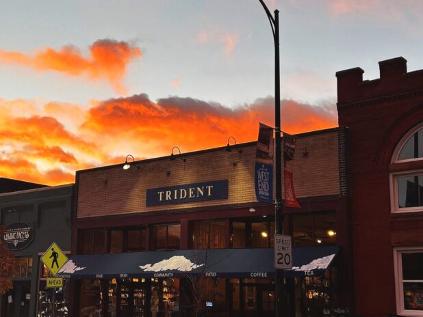 Trident Booksellers & Café storefront at sunset with orange clouds