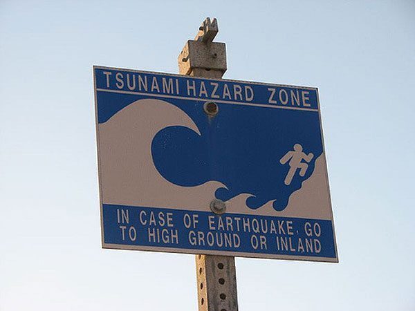 Blue tsunami hazard zone sign warning to go to high ground after earthquake